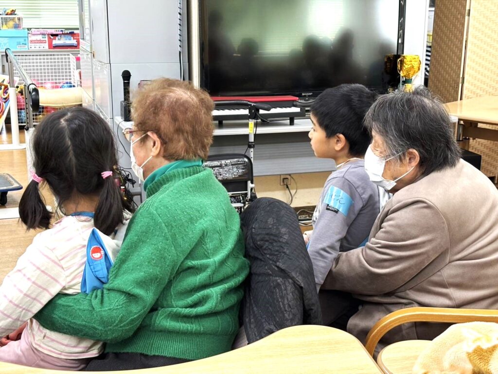 利用者様の膝上に乗り紙芝居に聴き入る園児さんたち